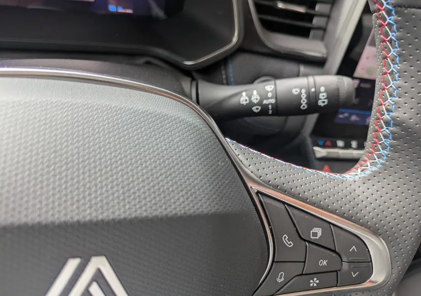 Détail du volant perforé avec surpiqûres tricolores et commandes intégrées, intérieur du Renault Symbioz 2026.