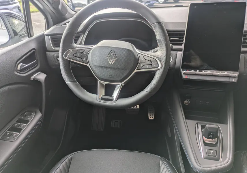 Vue intérieure centrée sur le volant Renault Symbioz gris avec écran tactile vertical et commandes au volant.