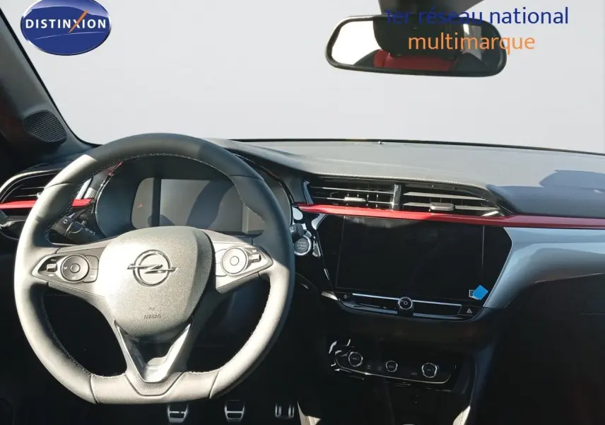 Vue intérieure du poste de conduite de l’Opel Corsa 1.2 Turbo 2023 avec volant cuir et tableau de bord noir et rouge.