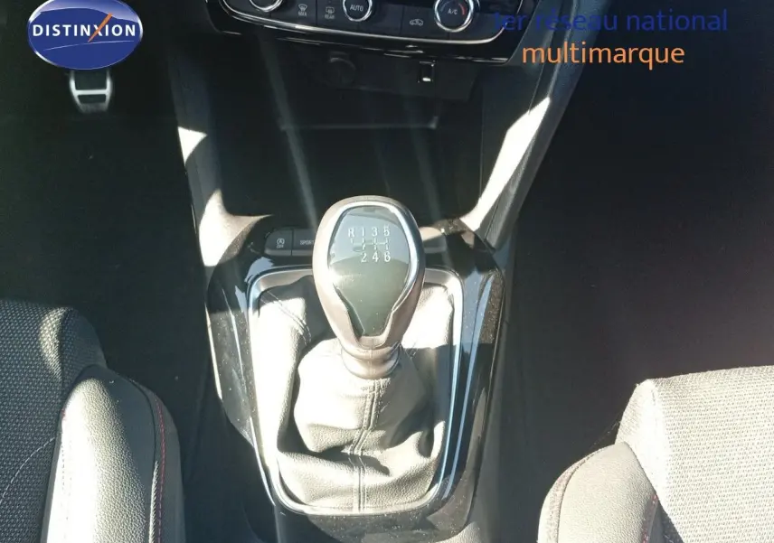 Le levier de vitesses manuel de l’Opel Corsa 2023 vu de dessus, entouré des sièges en tissu noir.