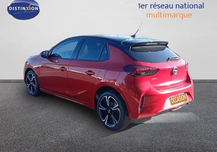 Opel Corsa rouge métal avec toit noir en 3/4 arrière droit, jantes alliage et feux arrière LED visibles.