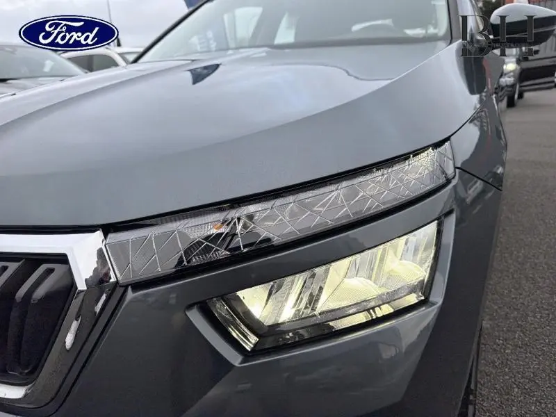 Gros plan sur le phare avant droit d'un Skoda Kamiq gris météore, mettant en valeur les détails du bloc optique moderne.