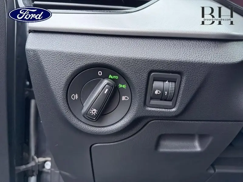 Gros plan sur le tableau de bord noir d'une Ford, montrant le sélecteur de phares et la molette de réglage d'intensité lumineuse.