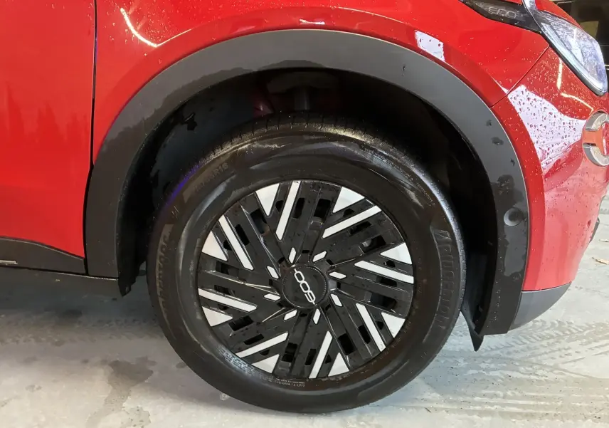 Gros plan sur la roue avant gauche d’une FIAT 600 rouge 2024, avec jante noire et argentée au design moderne.