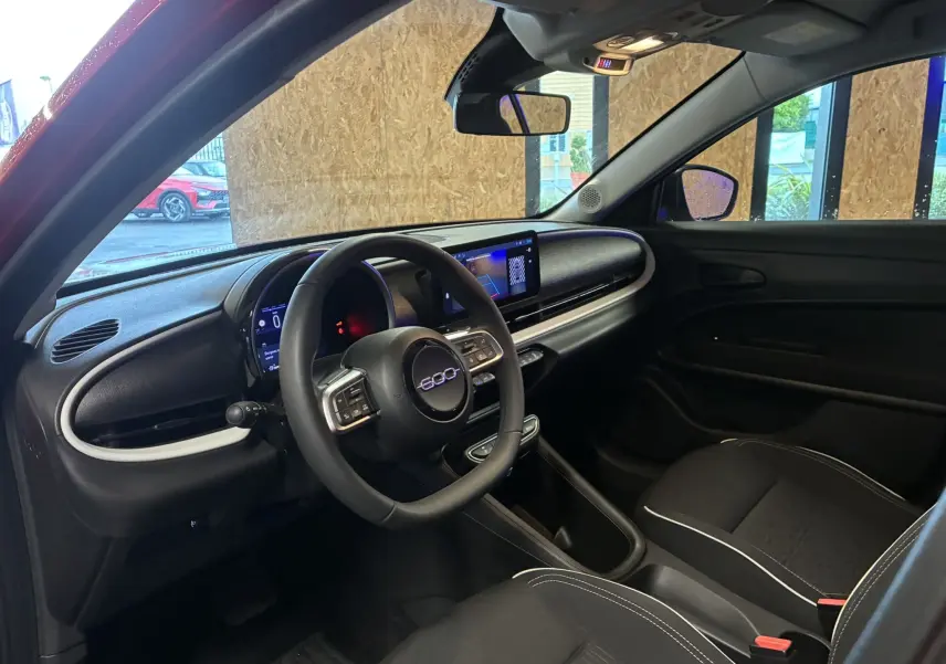 Intérieur noir de la FIAT 600 1.2 Hybrid 2024, vue côté conducteur avec tableau de bord digital et volant multifonction.