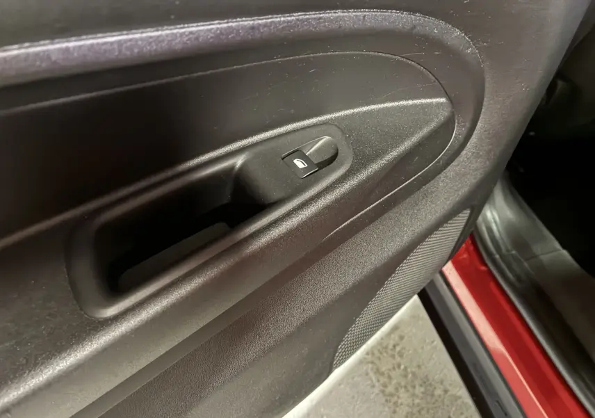 Détail de la commande de verrouillage de porte sur la portière intérieure noire d'une FIAT 600 rouge 2024.