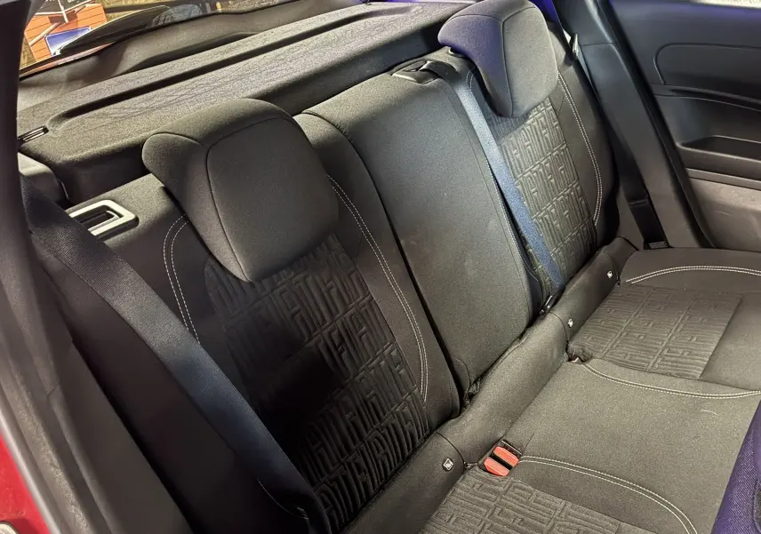 Vue intérieure du siège arrière côté droit d'une FIAT 600 rouge 2024 avec tissu noir et motifs FIAT embossés.