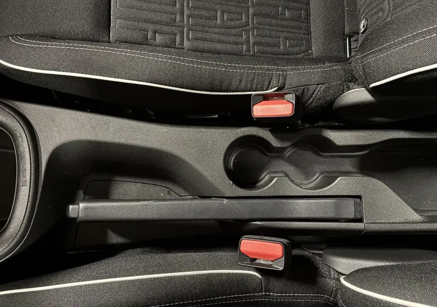 Vue plongeante sur la console centrale noire et les sièges tissu noir avec surpiqûres blanches de la FIAT 600 1.2 Hybrid rouge 2024.