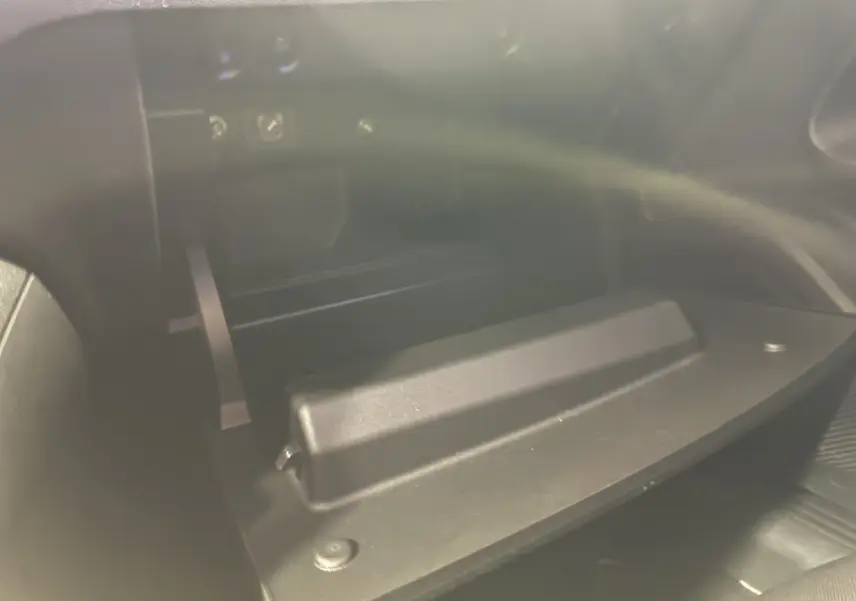 Gros plan sur la boîte à gants ouverte de l'intérieur, montrant le compartiment noir du Fiat 600 1.2 Hybrid 2024.