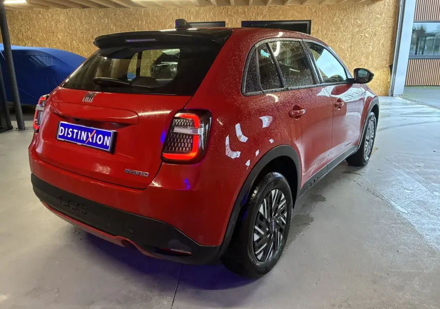 Vue 3/4 arrière droite d'une FIAT 600 1.2 Hybrid 2024 rouge avec feux arrière LED et jantes stylisées.