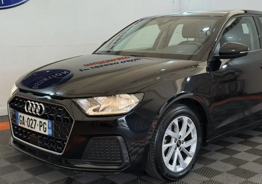 Audi A1 noir vue 3/4 avant droit, avec calandre hexagonale et jantes alliage argentées visibles.
