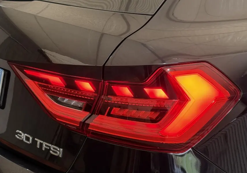 Gros plan sur le feu arrière droit rouge allumé d'une Audi A1 noire avec logo 30 TFSI visible.