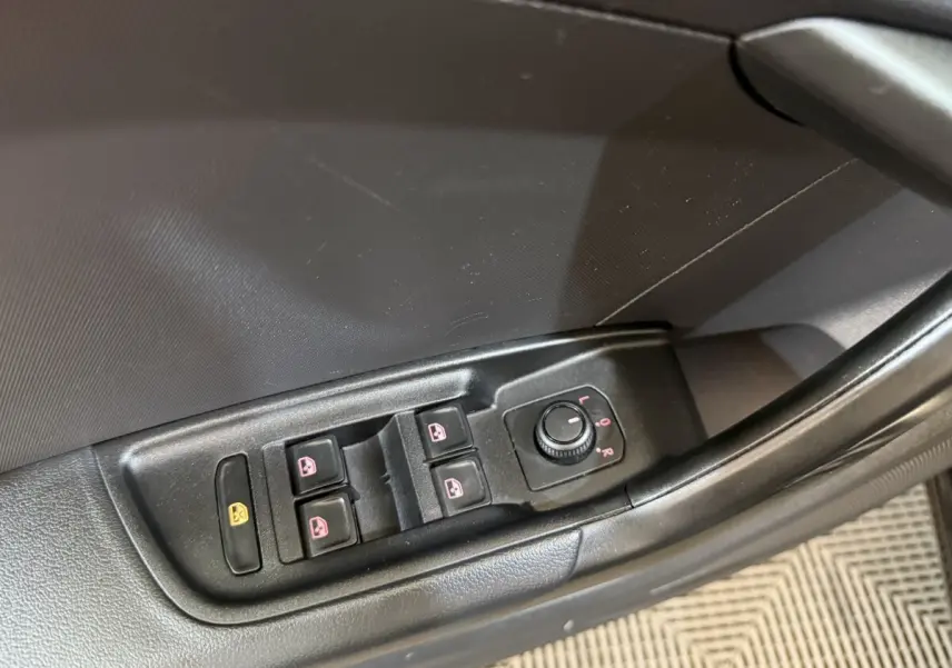 Gros plan sur les commandes des vitres et des rétroviseurs côté conducteur d’une Audi A1 noire de 2021.