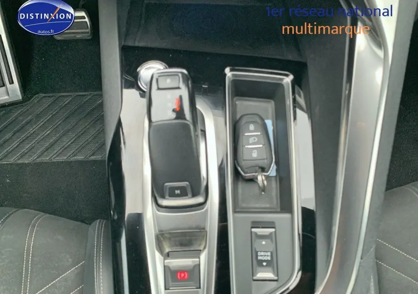 Vue rapprochée de la console centrale noire brillante du Peugeot 3008 gris platinium avec levier de vitesse et clé.
