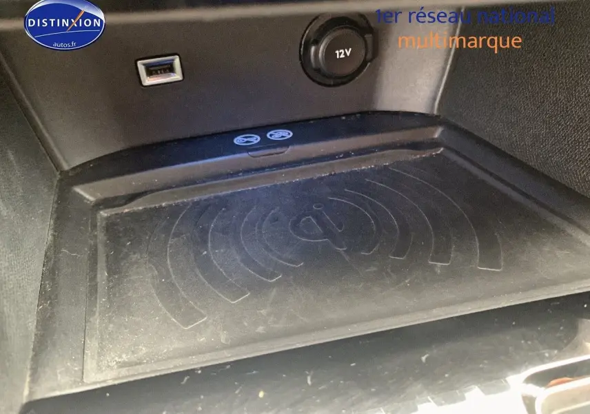 Gros plan sur la zone de recharge sans fil Qi et prise 12V dans l'habitacle du Peugeot 3008 gris platinium.