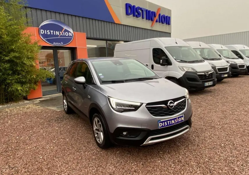 Opel Crossland X gris métallisé en 3/4 avant droit, stationné devant un concessionnaire Distinxion.