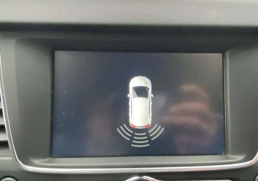 Écran central affichant l’aide au stationnement arrière d’une Opel Crossland X, vue en plan du véhicule blanc.