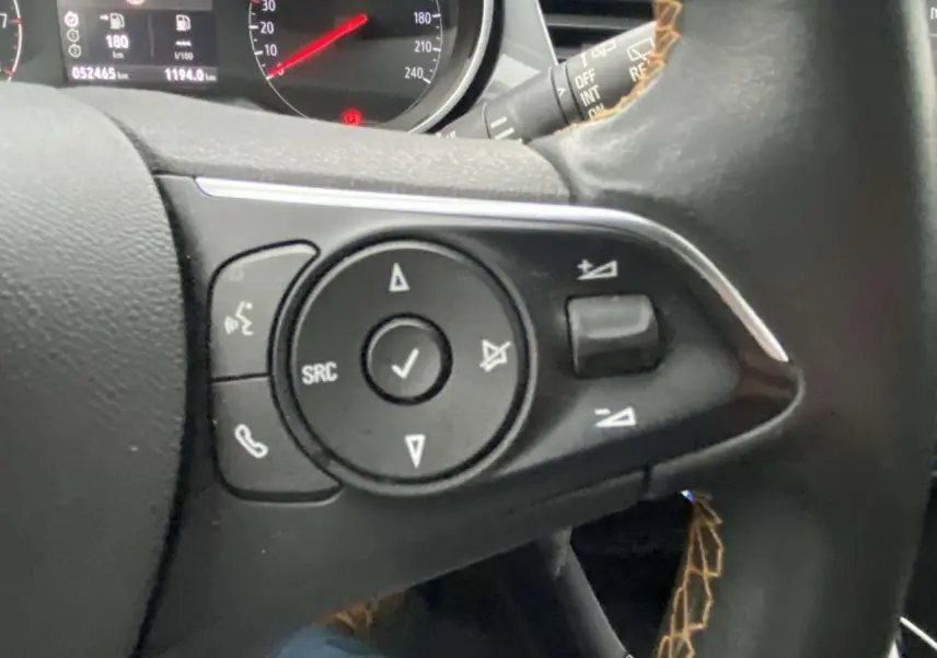 Gros plan sur les commandes au volant à gauche de l'Opel Crossland X 2020, tableau de bord partiellement visible.