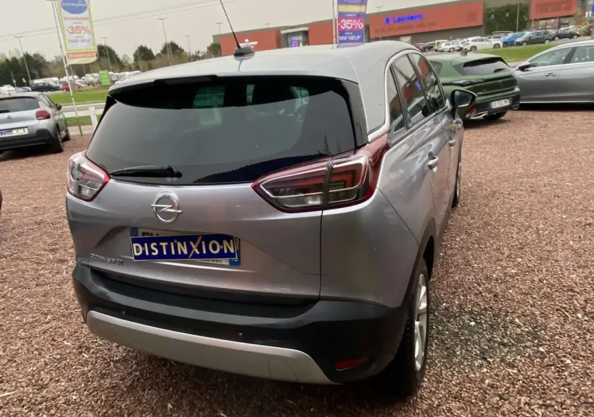 Vue 3/4 arrière d'un Opel Crossland X gris métallisé avec jantes alliage 16'' et vitres surteintées en extérieur.