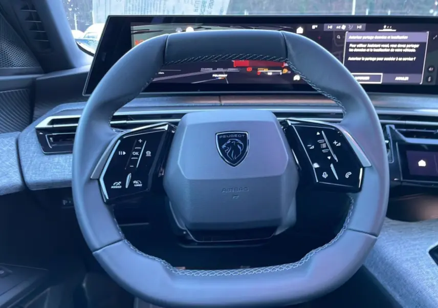 Volant cuir multifonctions Peugeot 5008 Hybrid 2026 vu de face avec tableau de bord numérique panoramique.
