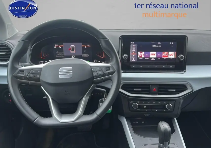 Vue intérieure centrée sur le volant méplat et le tableau de bord digital du SEAT Arona 2025 finition Copa, ambiance grise.