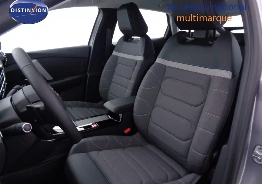 Vue intérieure côté conducteur de la Citroën C4 2023 gris Artense, sièges tissu et cuir noir avec surpiqûres bleues.