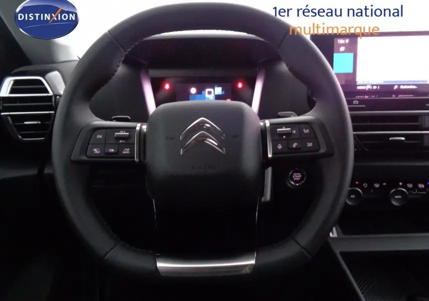 Vue intérieure centrée sur le volant noir de la Citroën C4 2023 avec tableau de bord digital et commandes intégrées.