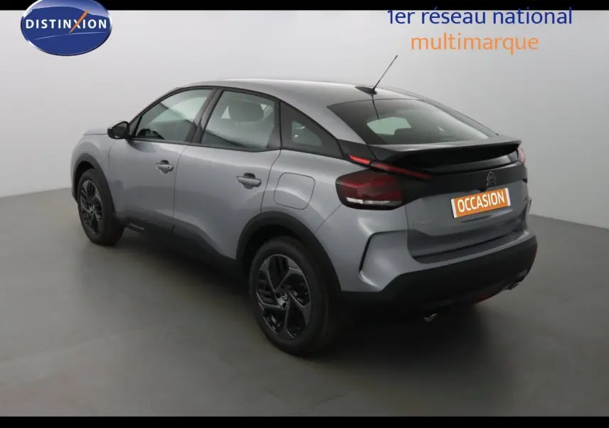 Vue 3/4 arrière droite d'une Citroën C4 gris Artense métal avec toit noir et jantes noires dans un studio.