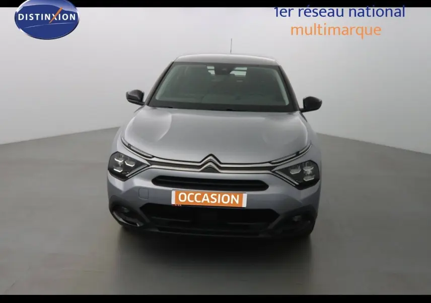 Vue frontale d'une Citroën C4 gris Artense métal 2023 avec calandre distinctive et phares LED allumés.
