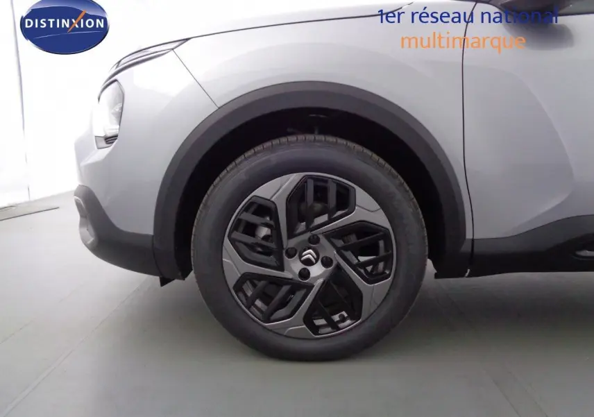 Gros plan sur la roue avant gauche d'une Citroën C4 gris Artense métal, avec jante alliage au design moderne.