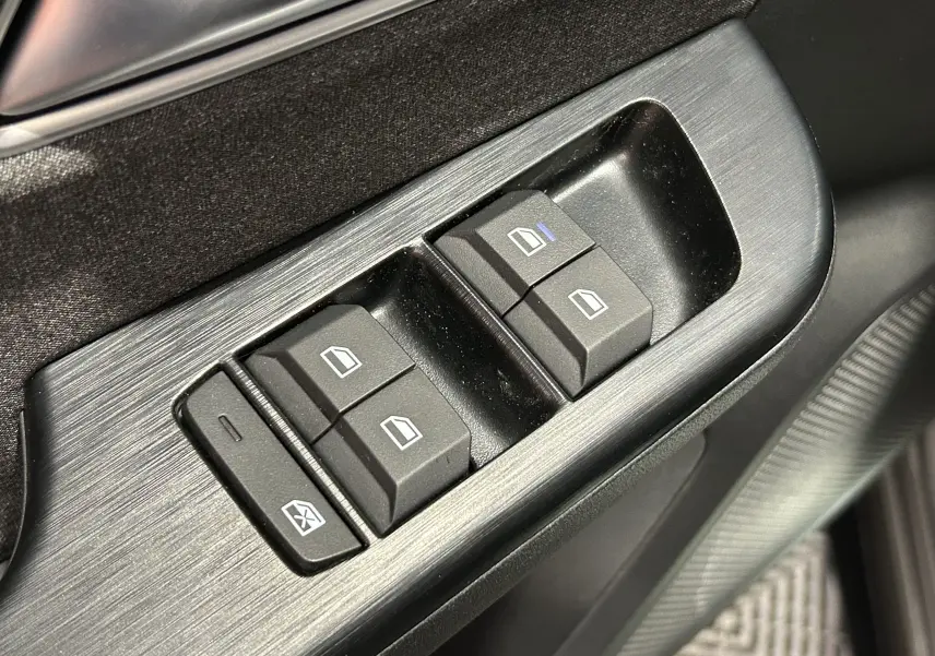 Gros plan sur les commandes de lève-vitres côté conducteur du MG ZS Cosmic Silver, finition intérieure noire.