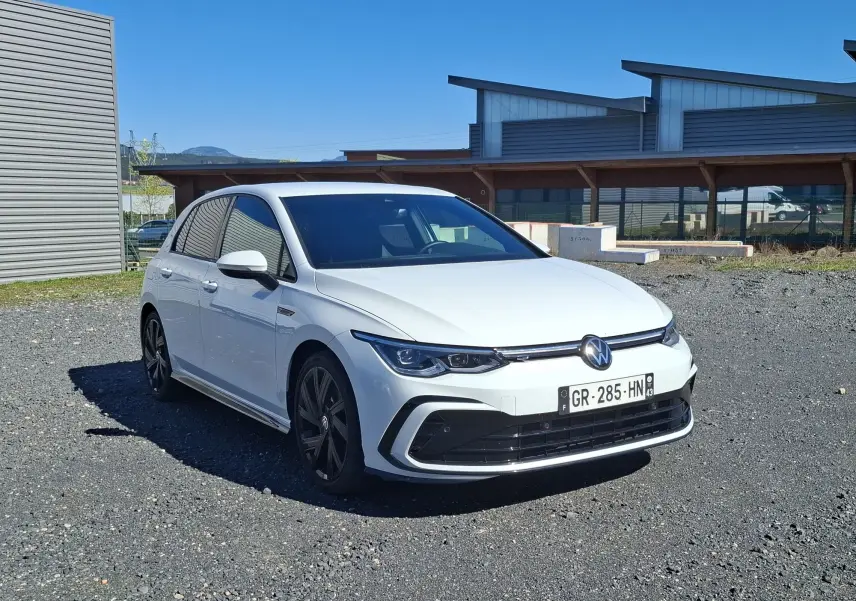 Volkswagen Golf 1.5 E-TSI R-Line blanche vue 3/4 avant, jantes noires et vitres arrière surteintées.