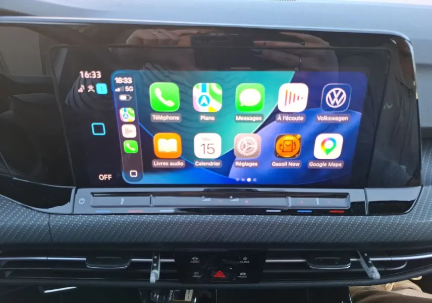 Écran tactile central affichant Apple CarPlay dans l’habitacle d’une Volkswagen Golf blanche, vue de face.