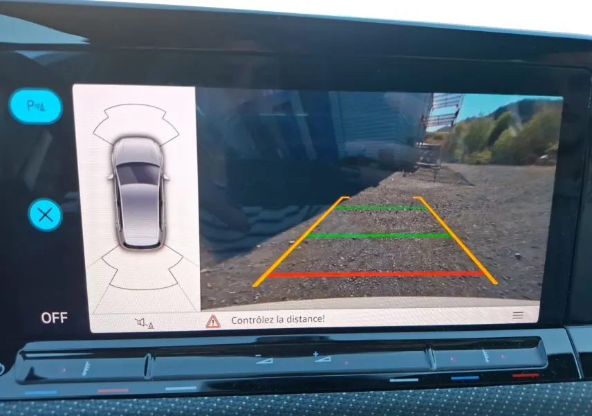 Vue de l'écran de la caméra de recul de la Volkswagen Golf blanche 2023, avec guidage coloré et capteurs de stationnement.