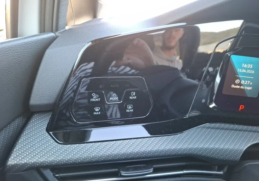 Gros plan sur les commandes de climatisation automatique noire dans l'habitacle d'une Volkswagen Golf blanche 2023.
