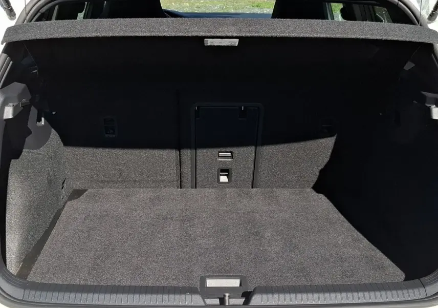 Coffre ouvert d’une Volkswagen Golf blanche 2023, vue arrière montrant l’espace de chargement tapissé de tissu gris.
