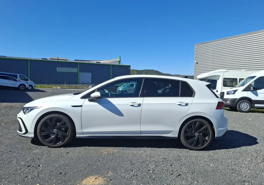 Vue de profil côté gauche d'une Volkswagen Golf blanche 2023 avec jantes noires et vitres arrière surteintées.