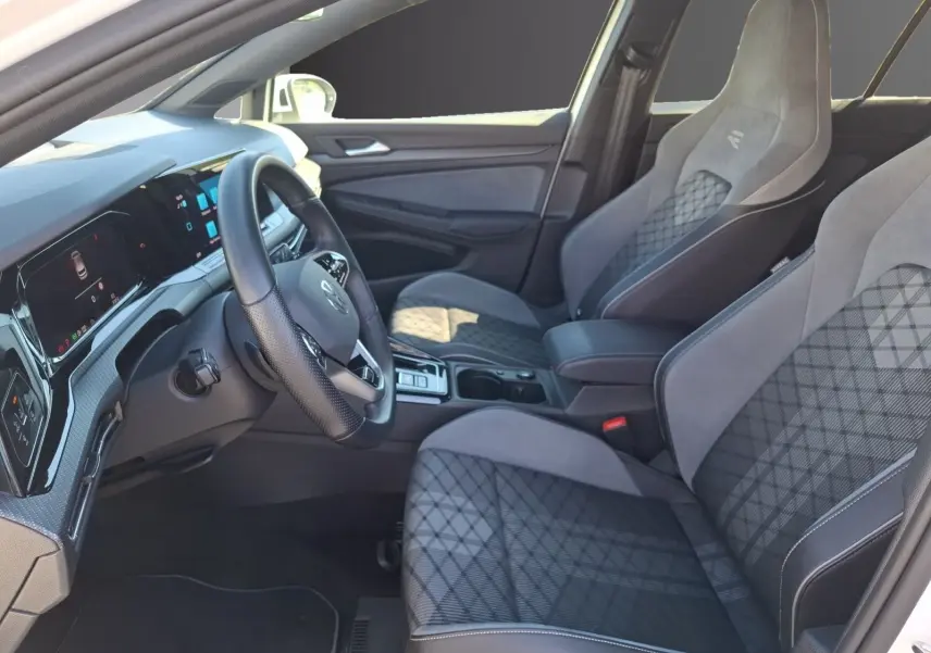 Vue intérieure côté conducteur de la Volkswagen Golf 1.5 E-TSI R-Line 2023 avec sièges sport gris et tableau de bord digital.