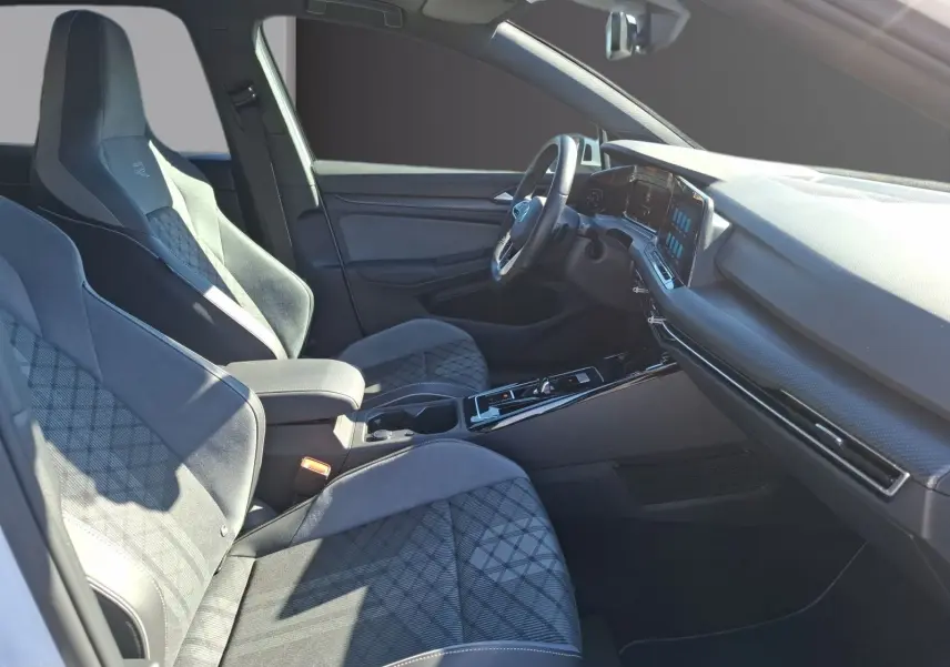 Vue intérieure côté conducteur de la Volkswagen Golf 1.5 E-TSI R-Line 2023 avec sièges sport en tissu gris et tableau de bord moderne.