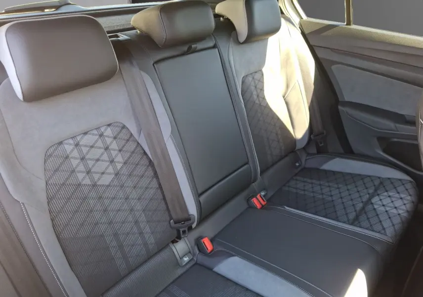 Vue intérieure des sièges arrière en tissu et alcantara avec motifs géométriques dans une Volkswagen Golf blanche 2023.