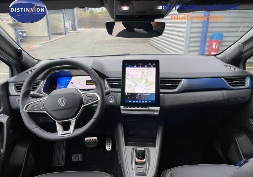 Vue intérieure avant du tableau de bord du Renault Symbioz gris Rafale métal avec écran tactile vertical et volant multifonction.