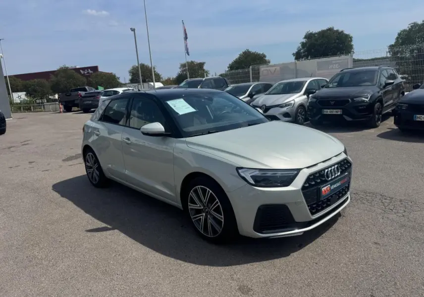 Audi A1 Sportback gris vue 3/4 avant droit sur parking, toit noir contrastant et jantes alliage visibles.
