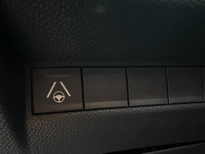 Bouton de contrôle d'assistance au maintien de voie sur tableau de bord noir d'une Peugeot 2008 bleu hybride.