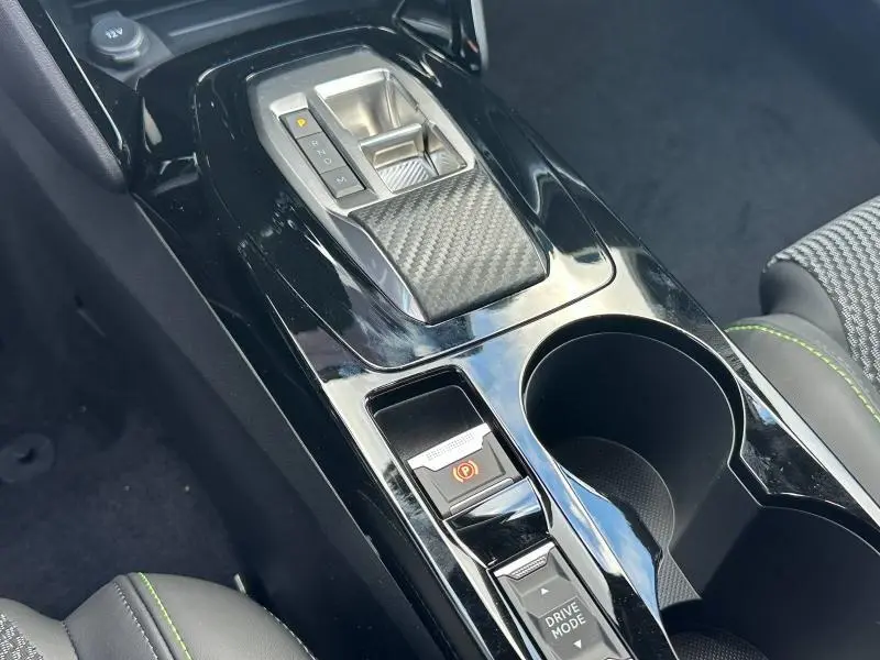 Gros plan sur la console centrale noire brillante avec levier de vitesses et boutons Drive Mode du Peugeot 2008 Hybrid bleu.