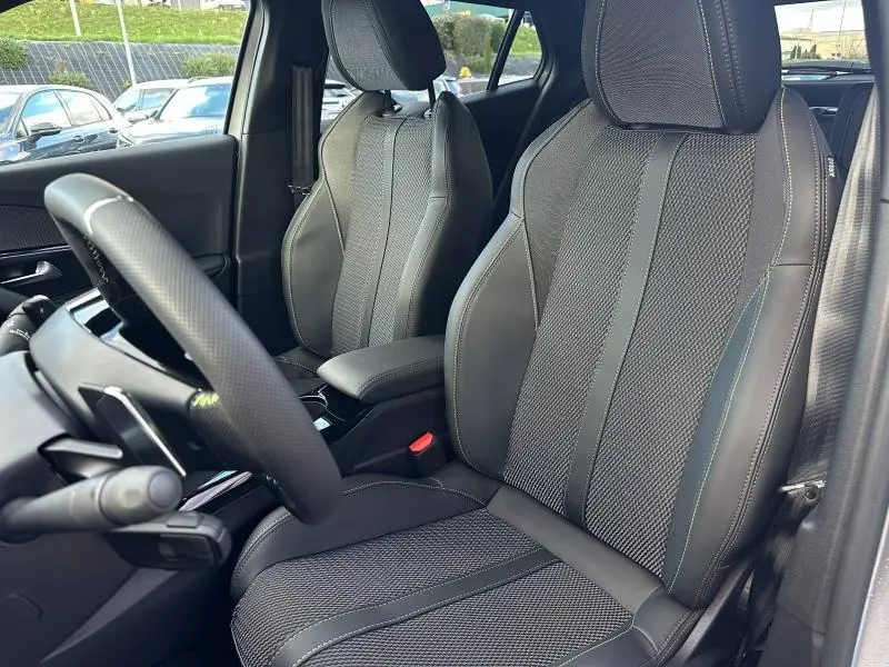 Vue intérieure rapprochée des sièges avant en tissu Belomka gris et volant cuir du Peugeot 2008 Hybrid 145ch GT 2025.