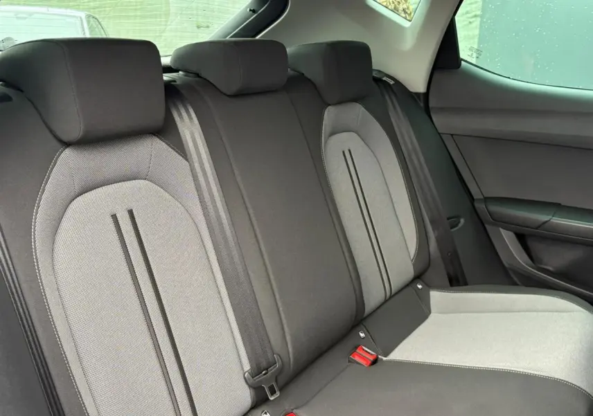 Vue intérieure des sièges arrière en tissu gris et noir du SEAT Leon 2024, avec ceintures de sécurité visibles.