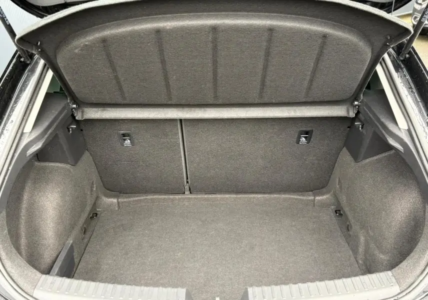 Coffre ouvert vu de l'arrière d'une SEAT LEON 2.0 TDI 150 DSG7 Business noir Minuit, espace de chargement vide et propre.