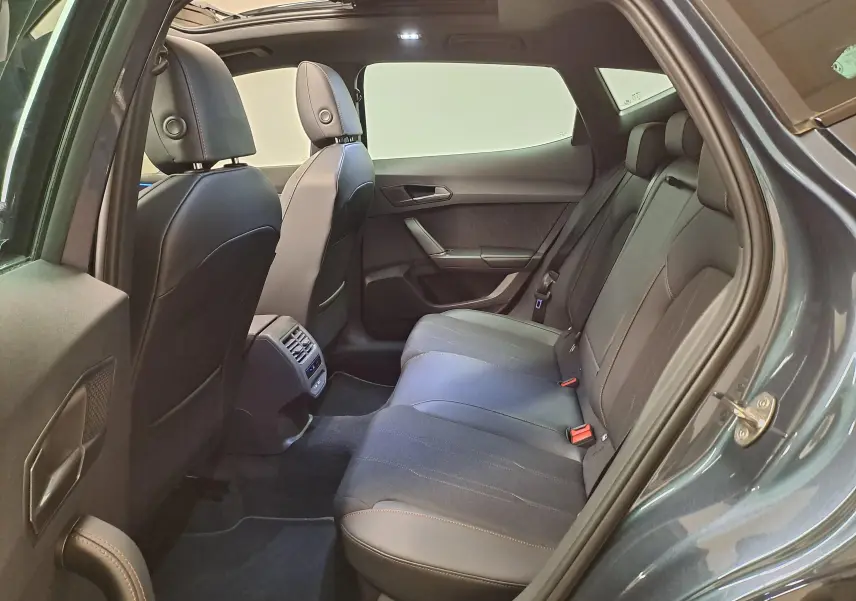 Vue côté droit de l'habitacle arrière du CUPRA Formentor gris magnétique avec toit ouvrant panoramique et sellerie noire.