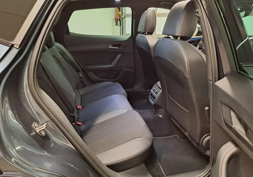 Vue intérieure côté arrière droit du CUPRA Formentor gris magnétique, montrant les sièges arrière en cuir noir et les aérations centrales.