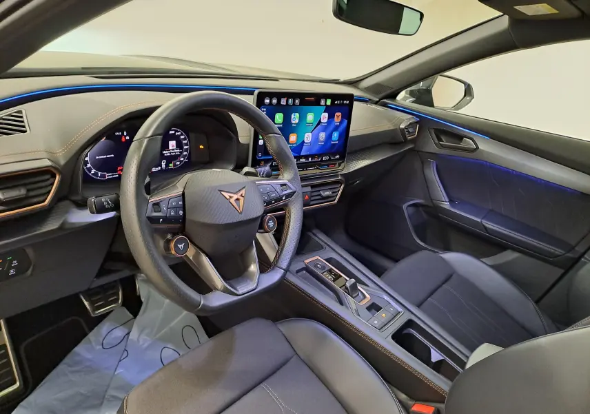 Vue intérieure côté conducteur du CUPRA Formentor 2025, volant cuir, écran tactile HD et éclairage d'ambiance bleu.